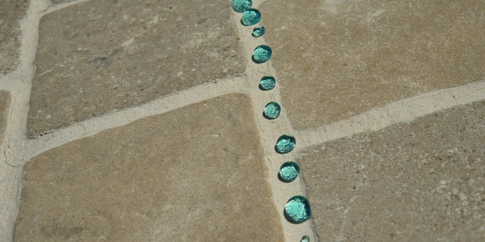 Sealed stone driveway, wet: water beading distinctly along the grout line